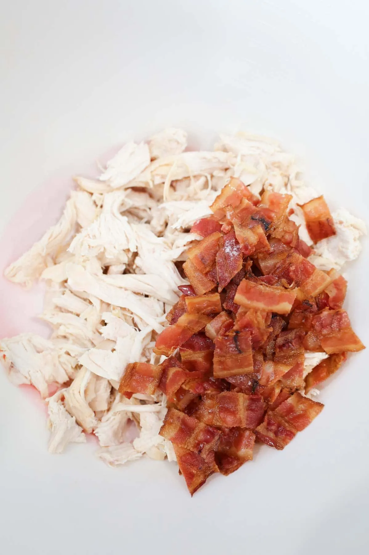 shredded chicken and chopped bacon in a mixing bowl