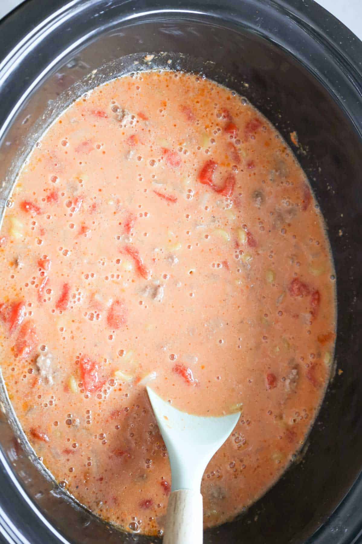 stirring macaroni noodles into sauce in a slow cooker