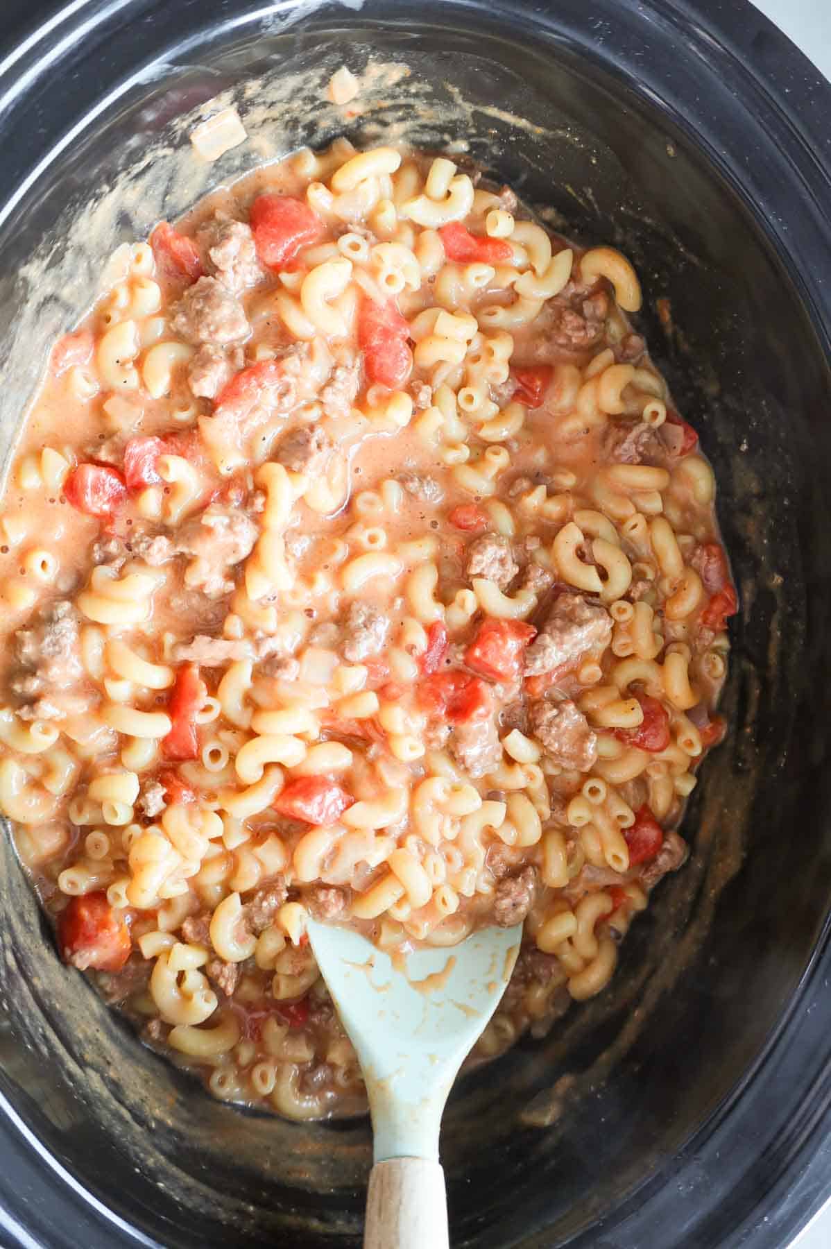 stirring hamburger macaroni in a crock pot