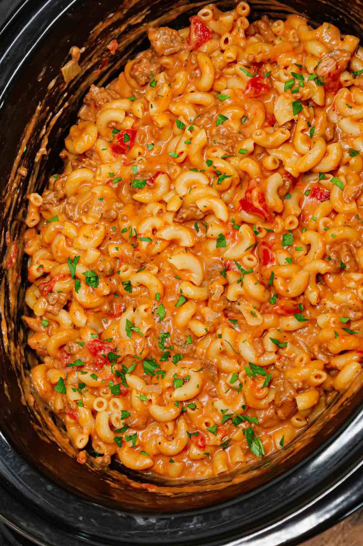 Crock Pot Hamburger Helper is a hearty slow cooker dish loaded with ground beef, diced onions, diced tomatoes, macaroni, cheddar soup and shredded cheddar cheese.