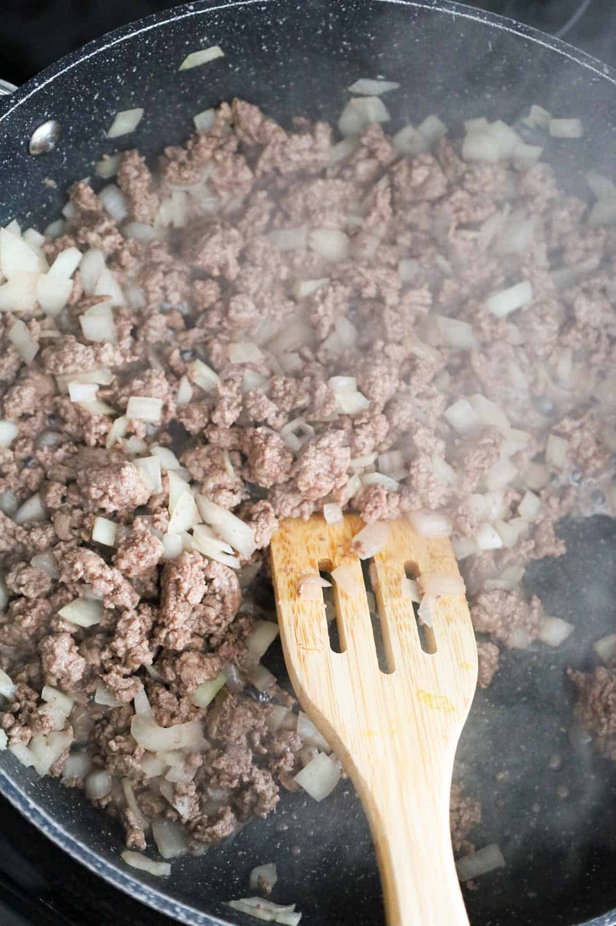 cooked ground beef and diced onions in a skillet