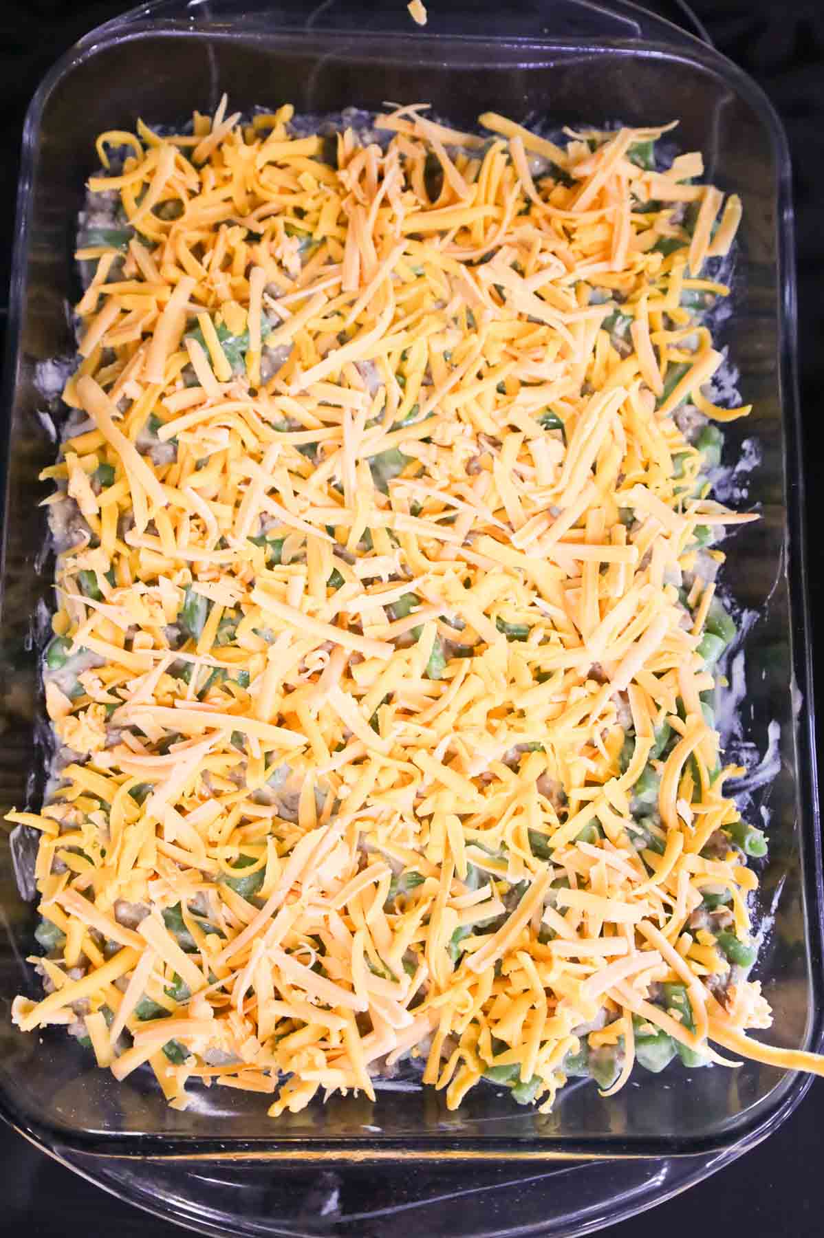shredded cheddar cheese sprinkled over green bean and ground beef casserole