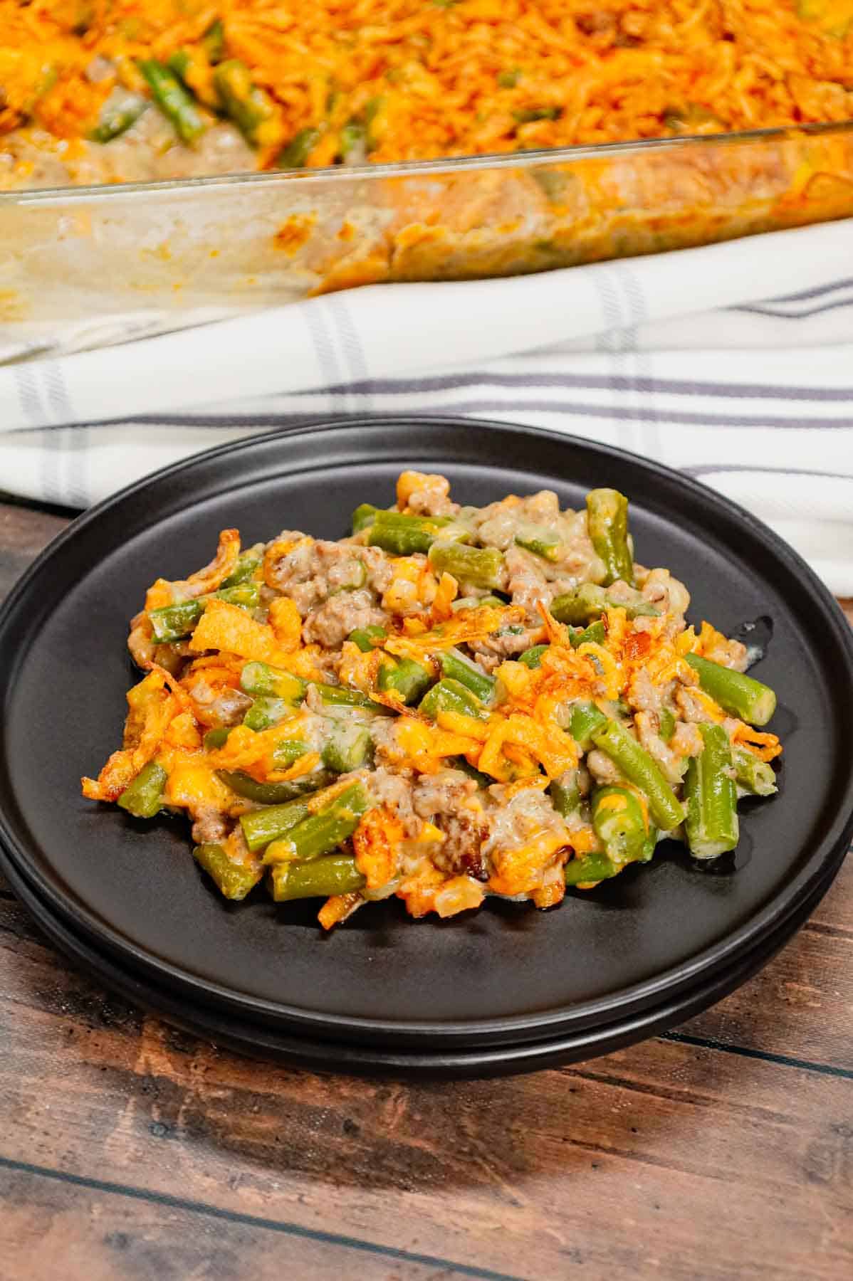 Hamburger Green Bean Casserole is a hearty ground beef casserole recipe loaded with cut green beans, cream of mushroom soup, diced onions, shredded cheddar cheese and French's crispy fried onions.