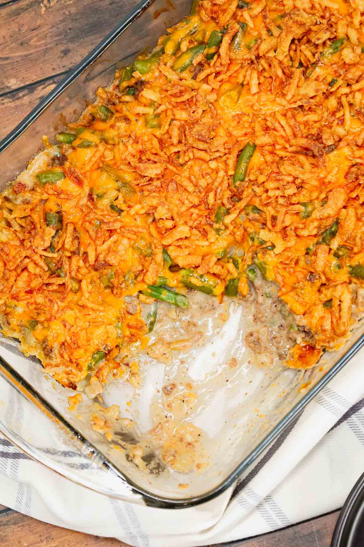 Hamburger Green Bean Casserole is a hearty ground beef casserole recipe loaded with cut green beans, cream of mushroom soup, diced onions, shredded cheddar cheese and French's crispy fried onions.