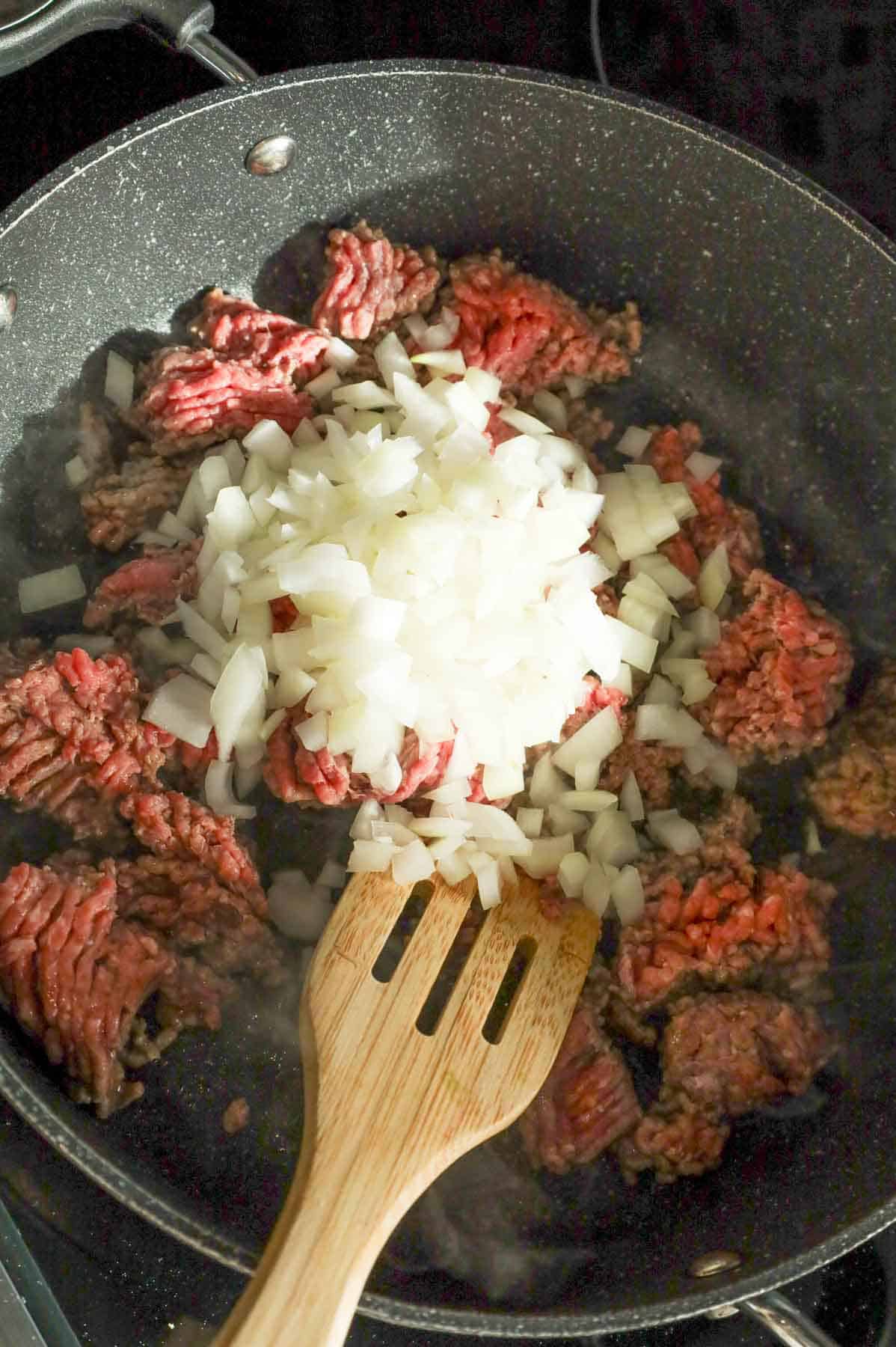 diced onions added to skillet with ground beef