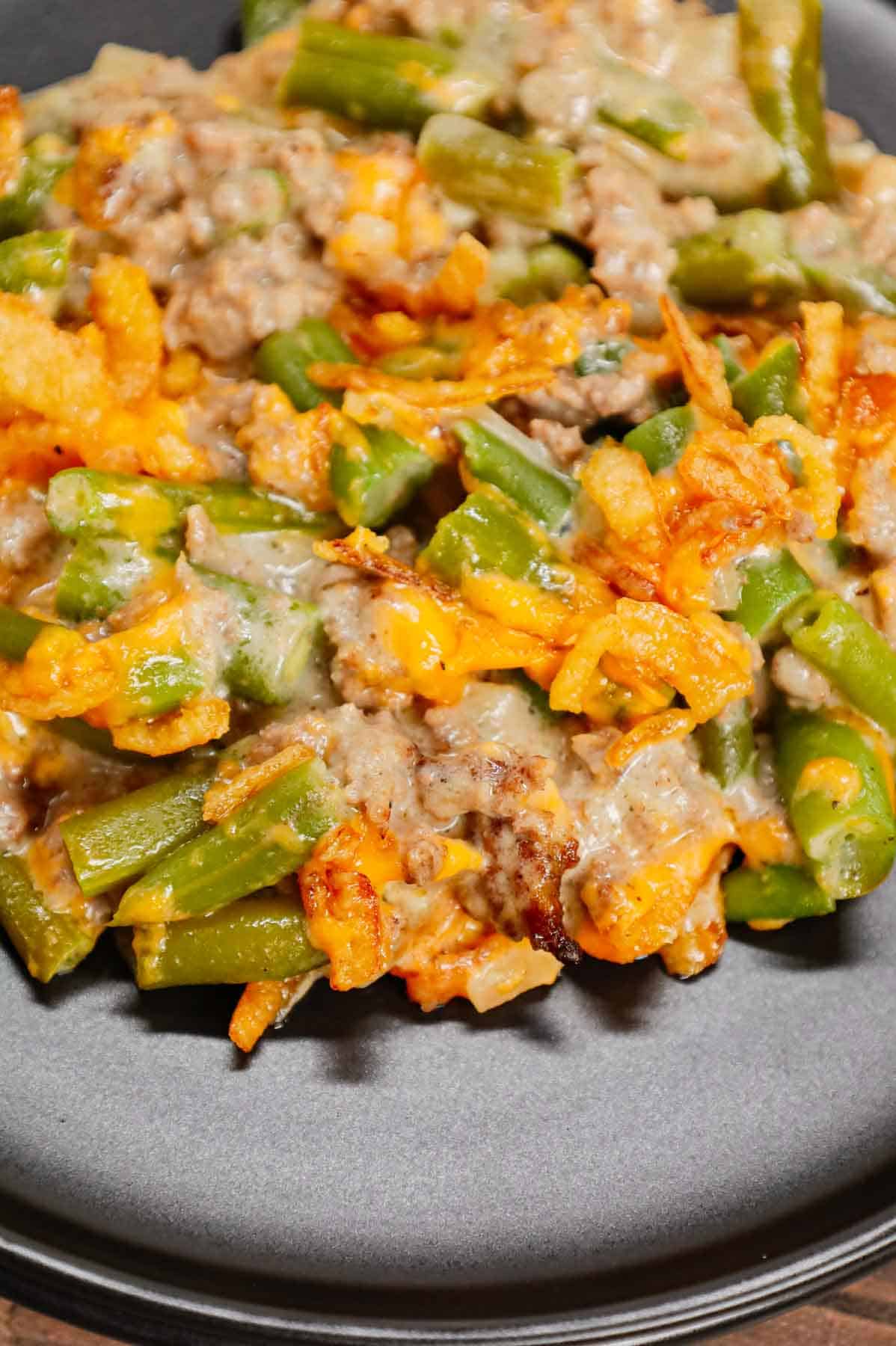 Hamburger Green Bean Casserole is a hearty ground beef casserole recipe loaded with cut green beans, cream of mushroom soup, diced onions, shredded cheddar cheese and French's crispy fried onions.