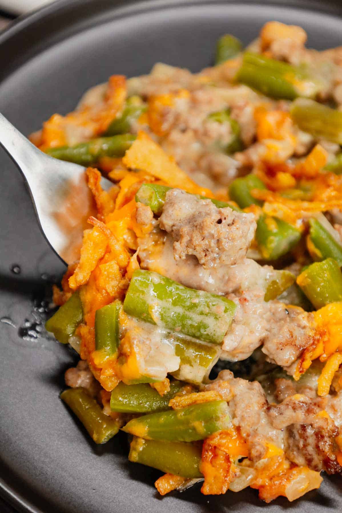 Hamburger Green Bean Casserole is a hearty ground beef casserole recipe loaded with cut green beans, cream of mushroom soup, diced onions, shredded cheddar cheese and French's crispy fried onions.