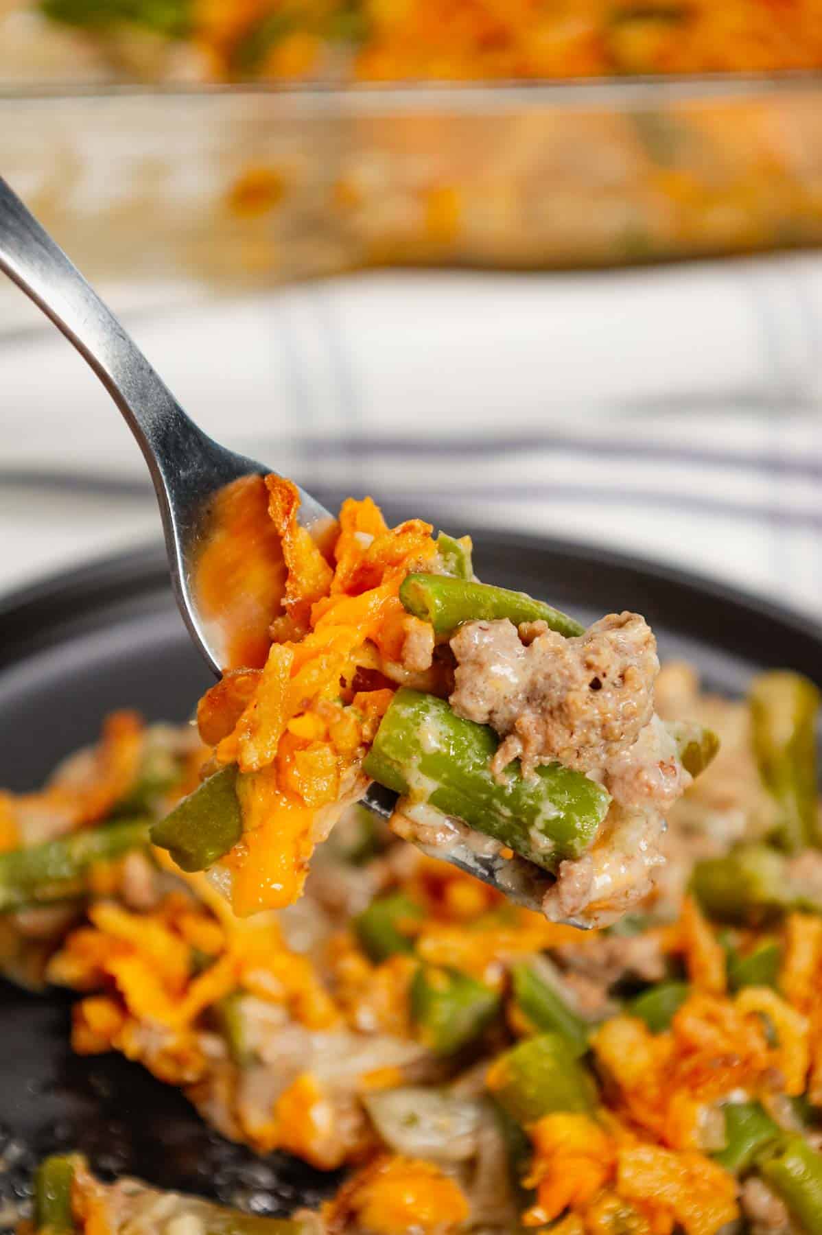 Hamburger Green Bean Casserole is a hearty ground beef casserole recipe loaded with cut green beans, cream of mushroom soup, diced onions, shredded cheddar cheese and French's crispy fried onions.