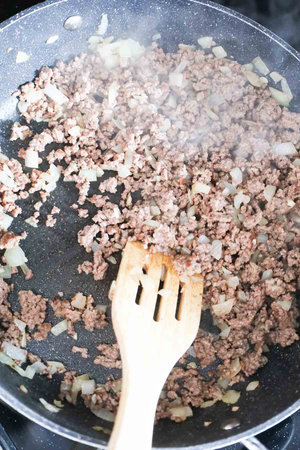 cooked ground beef and diced onions in a skillet