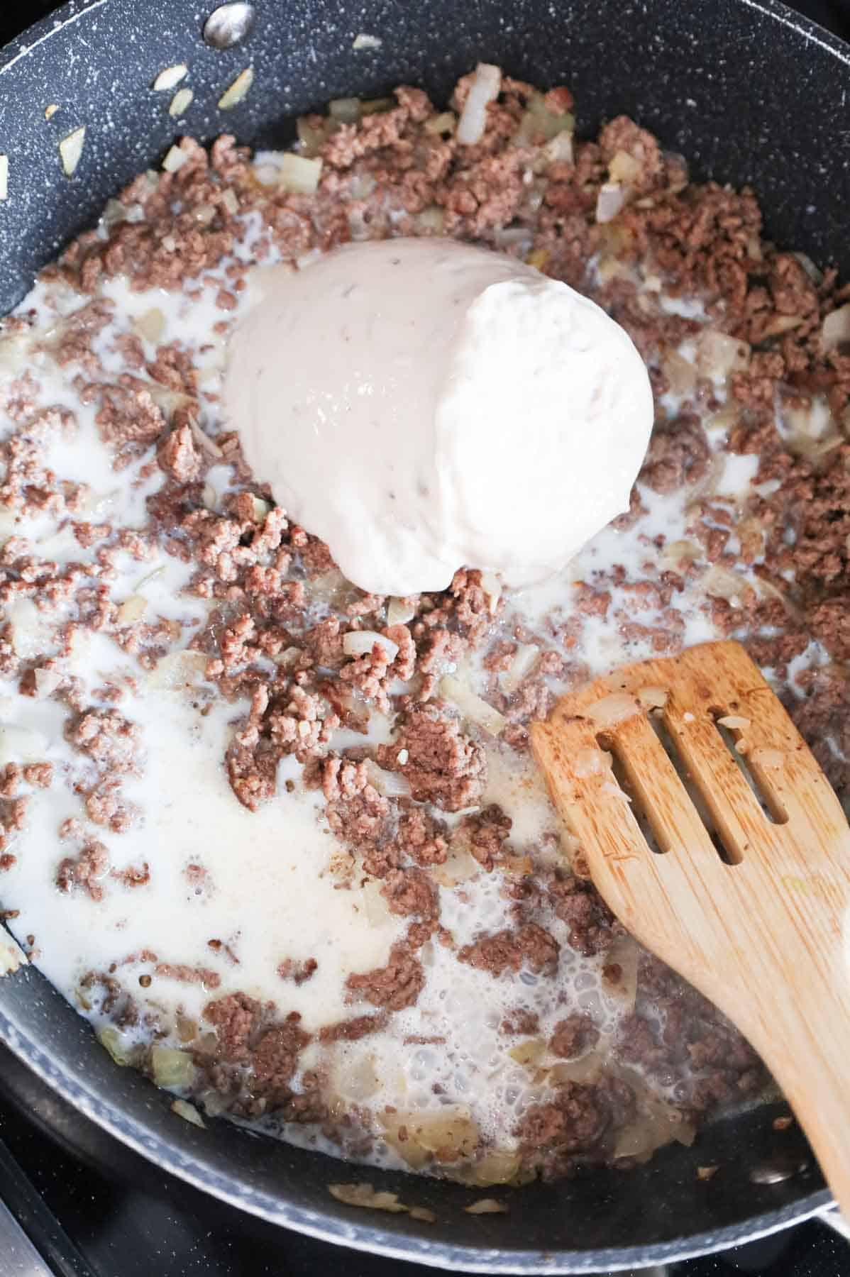 condensed cream of mushroom soup and milk added to skillet with cooked ground beef