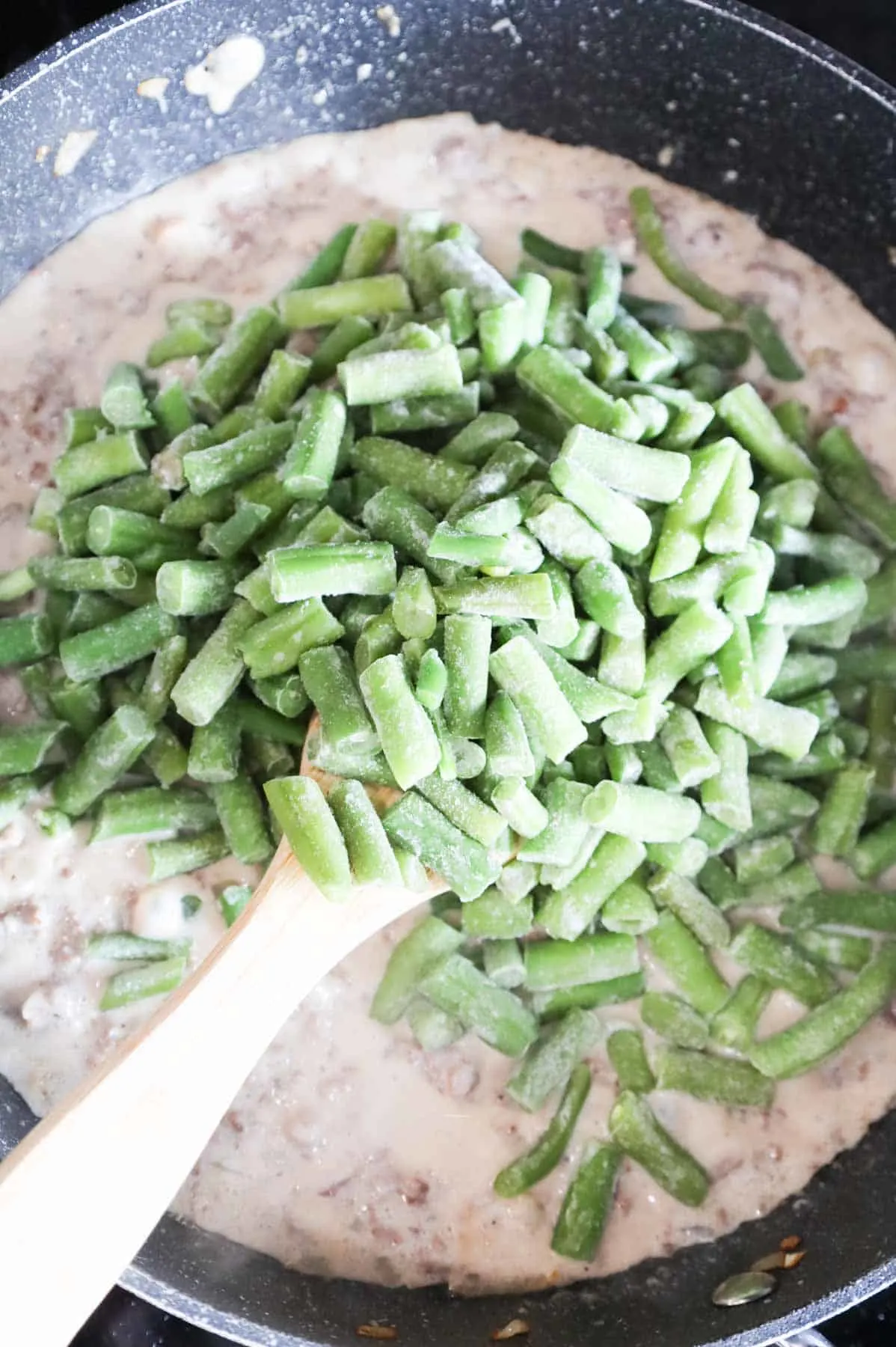 frozen cut green beans added to skillet with creamy ground beef mixture