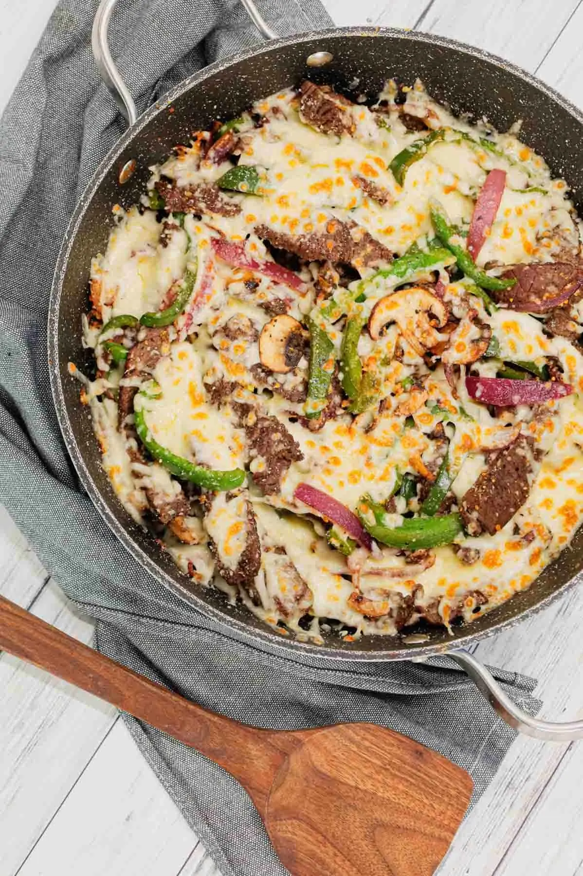 Philly Cheese Steak Skillet is a hearty dish loaded with steak strips, green bell peppers, red onions, sliced mushrooms and topped with a blend of mozzarella and provolone.
