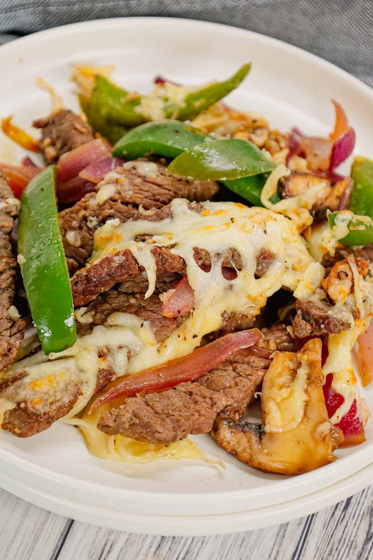 Philly Cheese Steak Skillet is a hearty dish loaded with steak strips, green bell peppers, red onions, sliced mushrooms and topped with a blend of mozzarella and provolone.