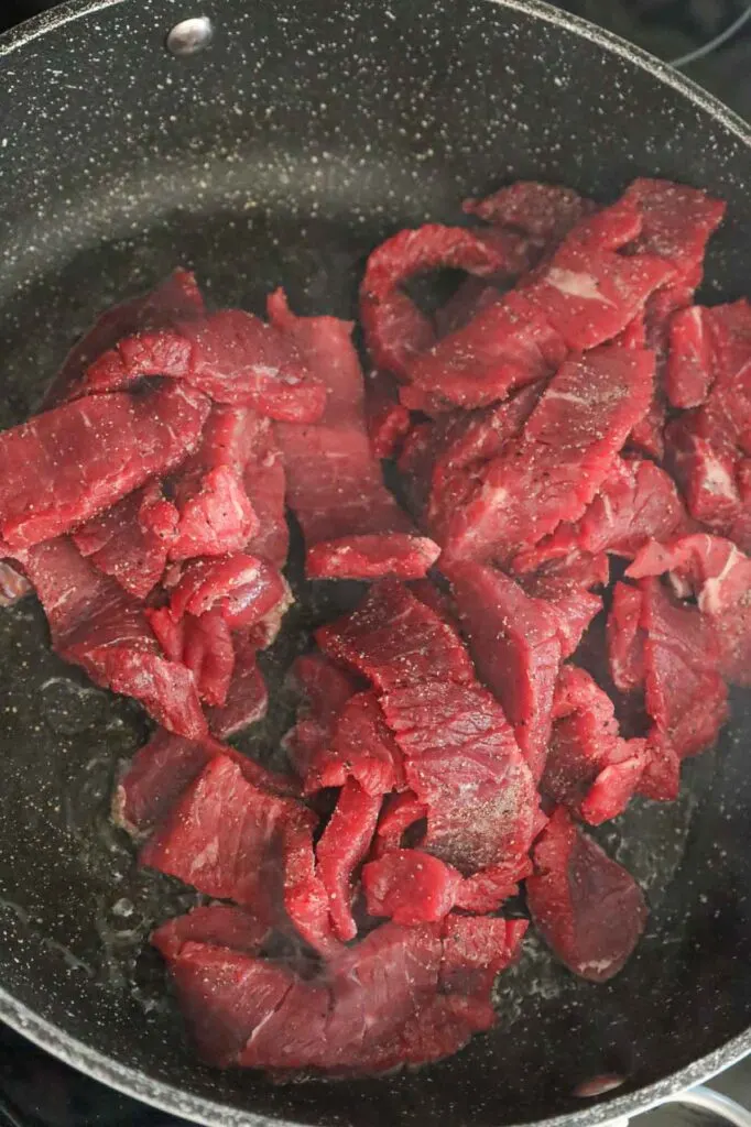 raw steak strips dropped in a hot skillet