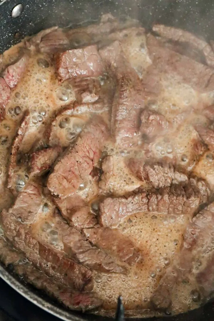 steak strips cooking in a skillet