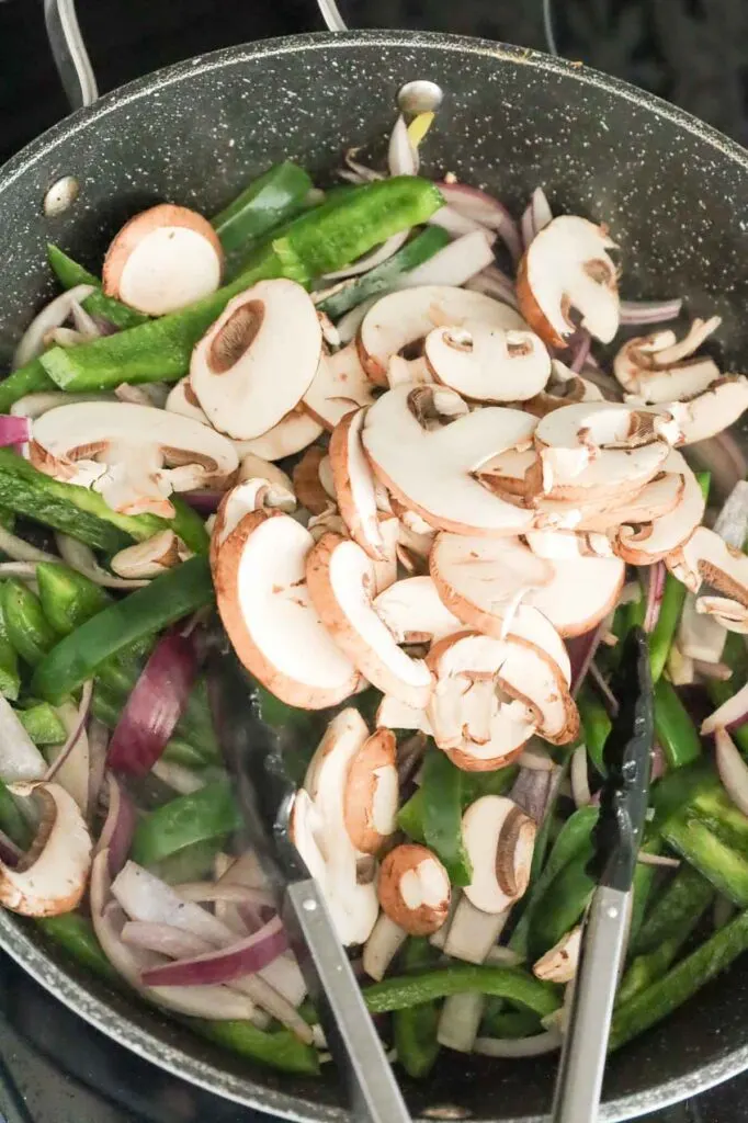 sliced mushrooms added to skillet with green peppers and red onions