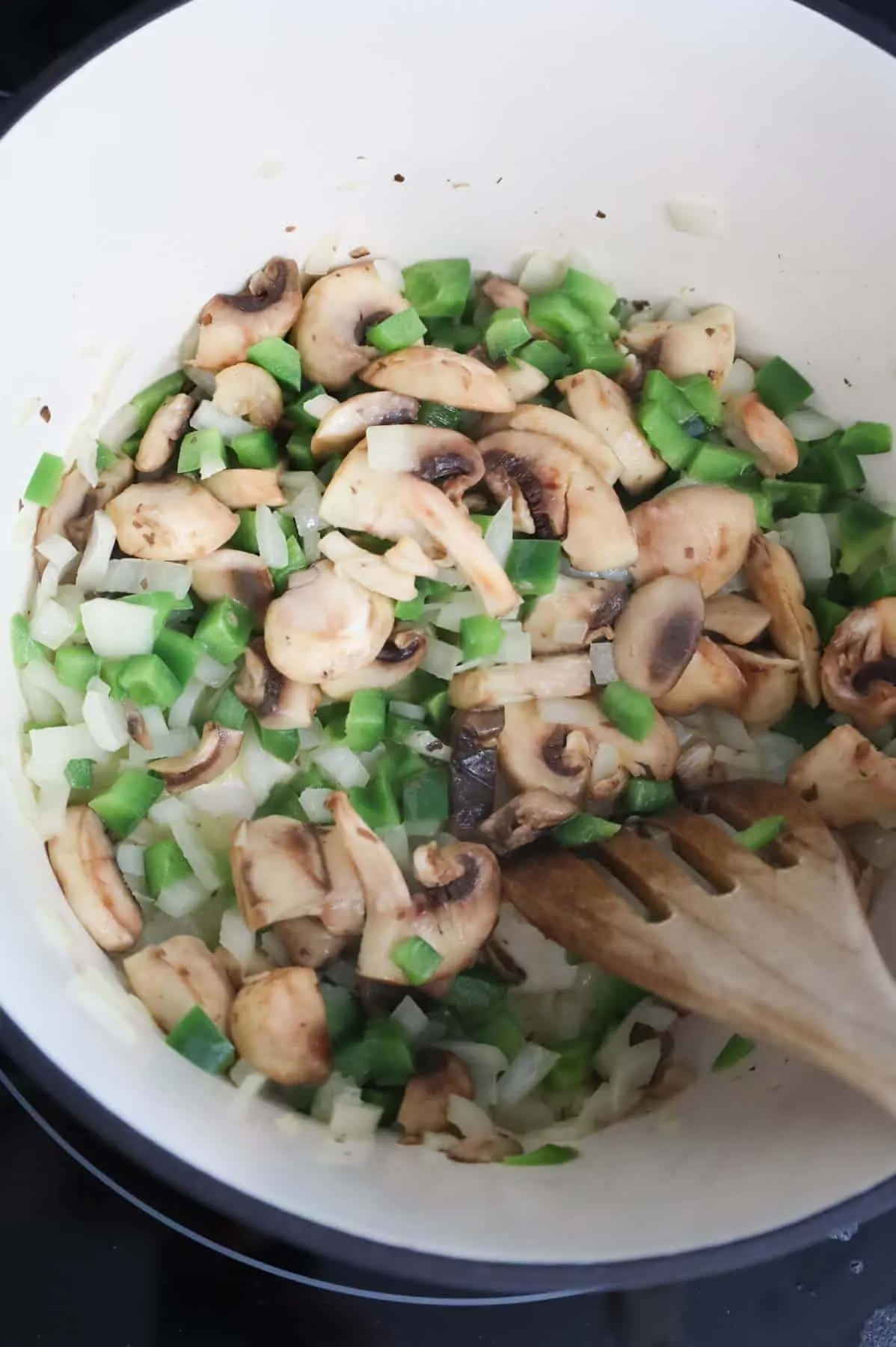 onions, green peppers and mushrooms cooking in a pot