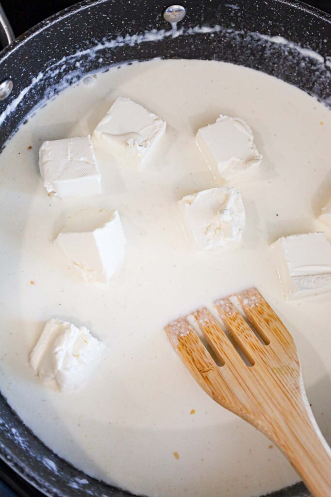 cubes of cream cheese added to skillet with cream sauce