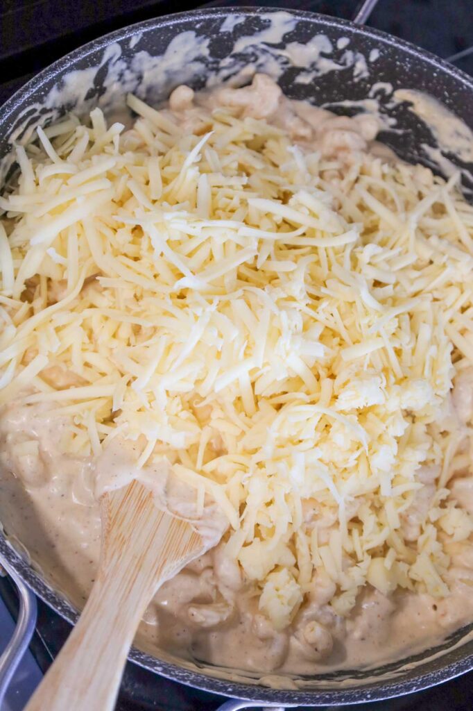 shredded white cheddar cheese added to skillet with creamy pasta