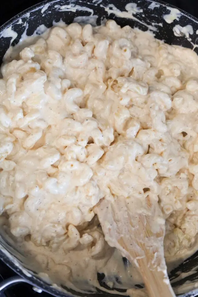 stirring creamy cavatappi pasta in a skillet