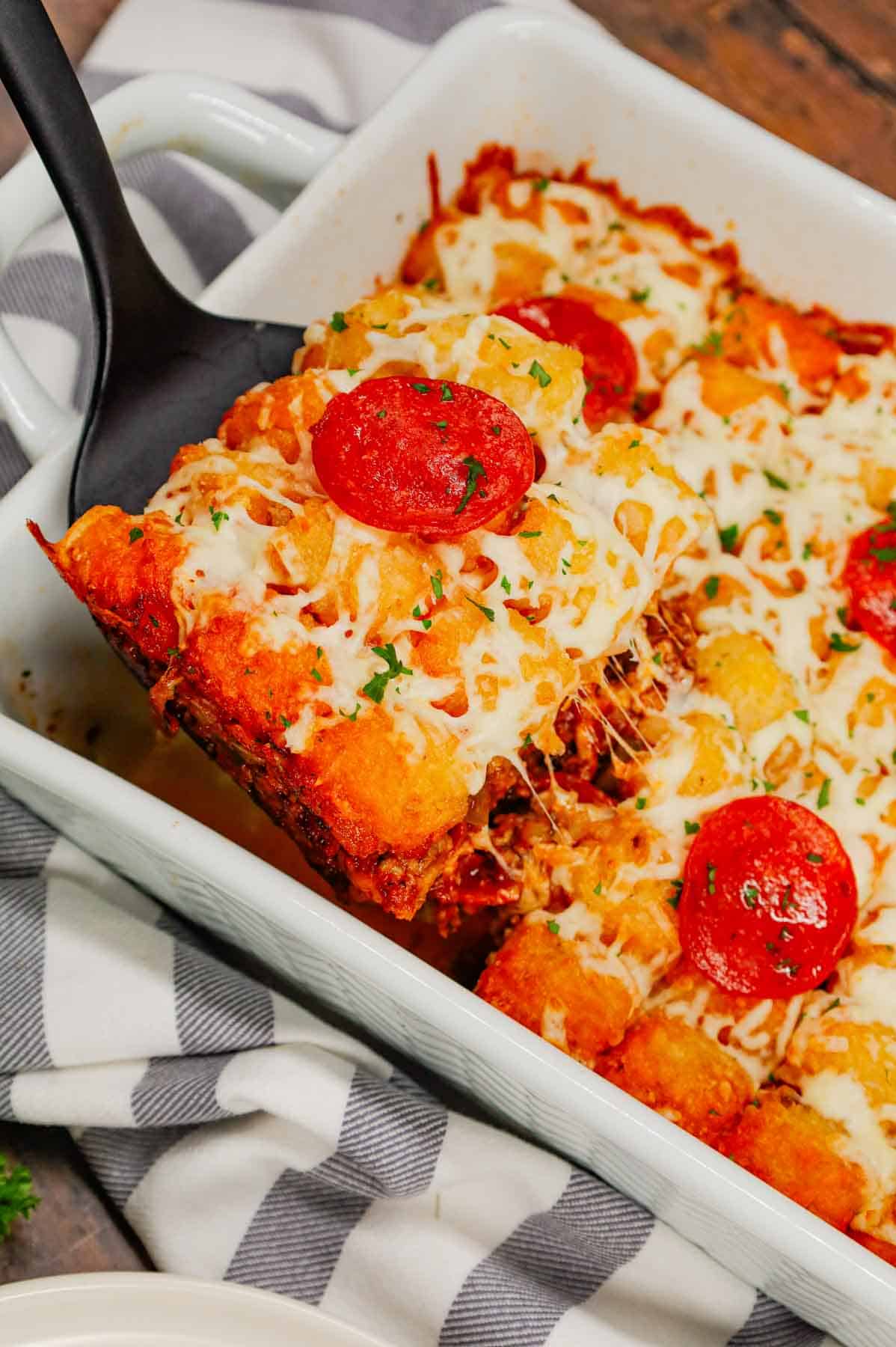 Pizza Tater Tot Casserole is a hearty casserole loaded with ground beef, Italian sausage, pepperoni, green peppers, onions, pizza sauce, mozzarella cheese and crispy tater tots.