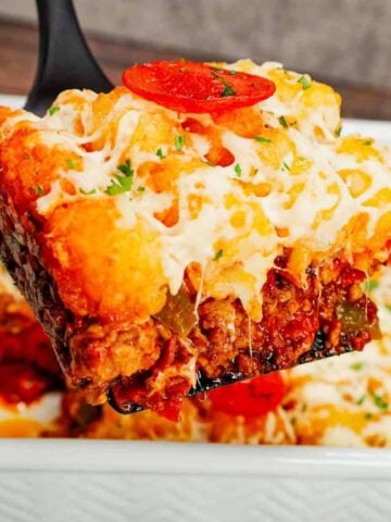 Pizza Tater Tot Casserole is a hearty casserole loaded with ground beef, Italian sausage, pepperoni, green peppers, onions, pizza sauce, mozzarella cheese and crispy tater tots.