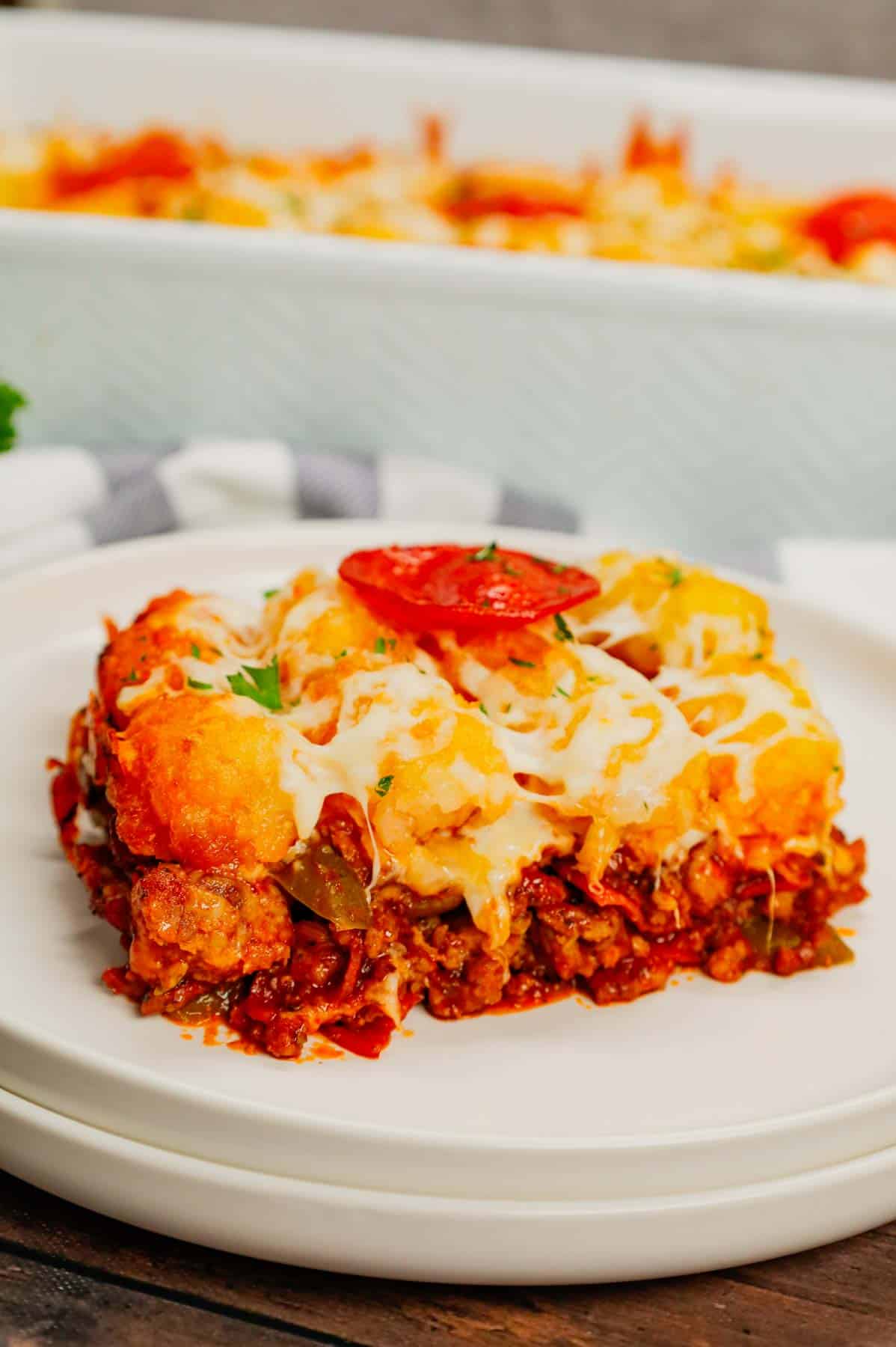 Pizza Tater Tot Casserole is a hearty casserole loaded with ground beef, Italian sausage, pepperoni, green peppers, onions, pizza sauce, mozzarella cheese and crispy tater tots.