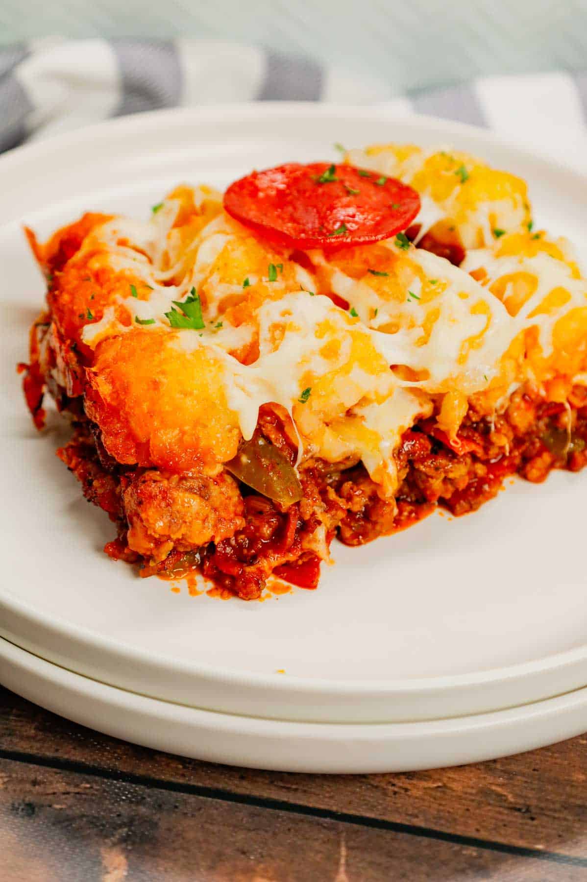 Pizza Tater Tot Casserole is a hearty casserole loaded with ground beef, Italian sausage, pepperoni, green peppers, onions, pizza sauce, mozzarella cheese and crispy tater tots.