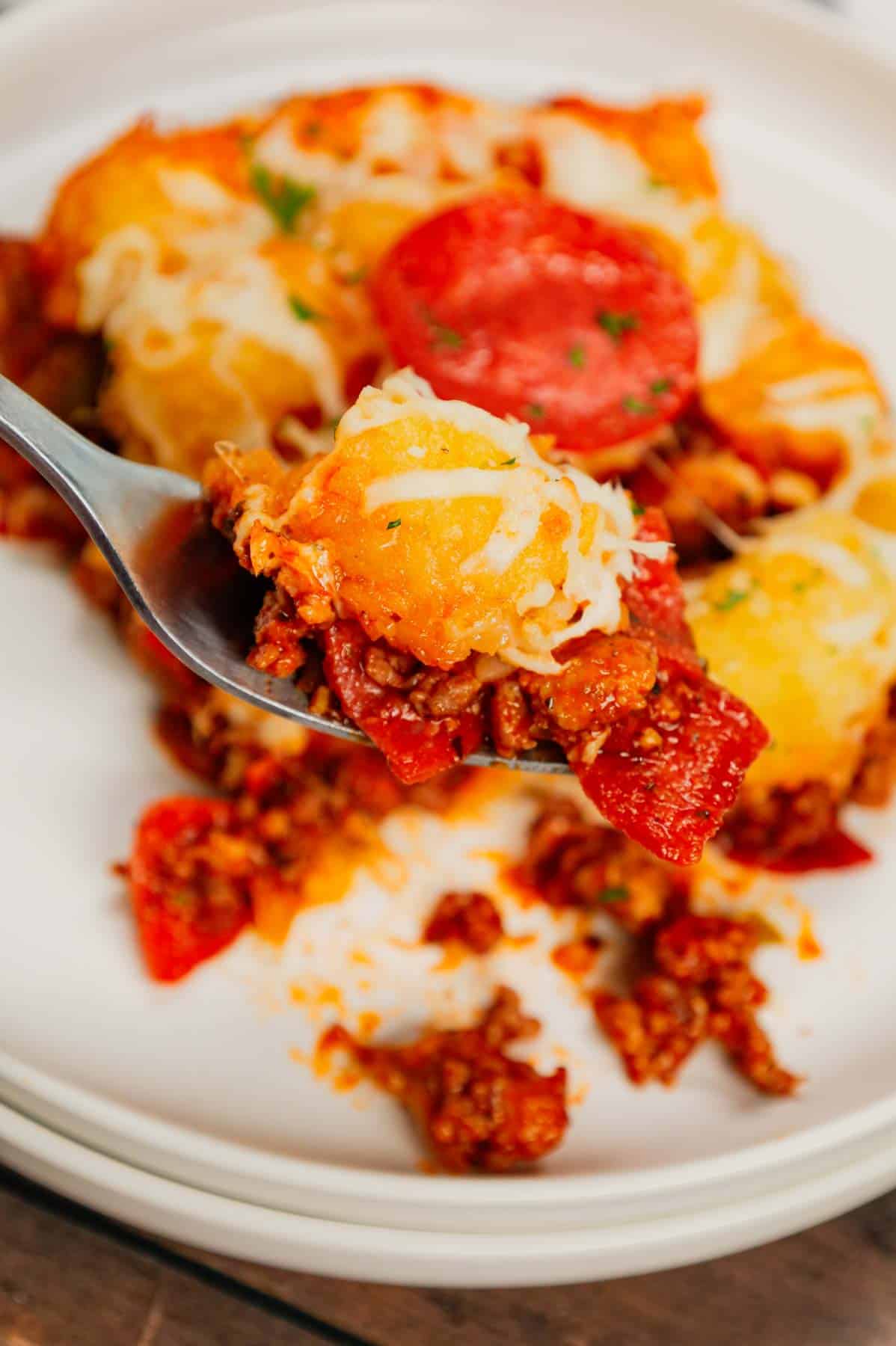 Pizza Tater Tot Casserole is a hearty casserole loaded with ground beef, Italian sausage, pepperoni, green peppers, onions, pizza sauce, mozzarella cheese and crispy tater tots.
