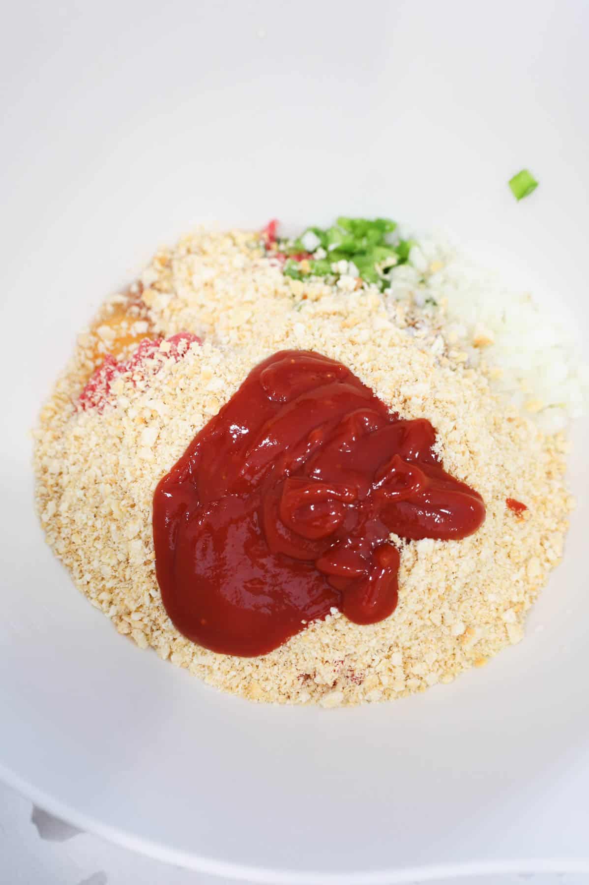 ketchup glaze mixture added to bowl with meatloaf ingredients