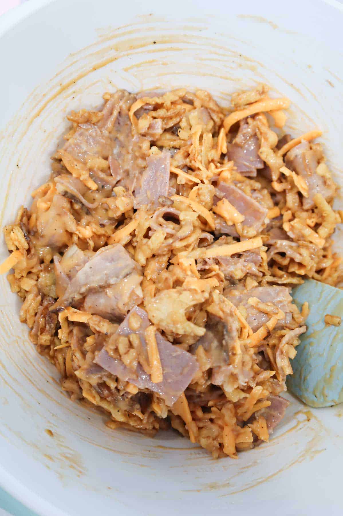 stirring cheddar cheese and roast beef mixture in a mixing bowl