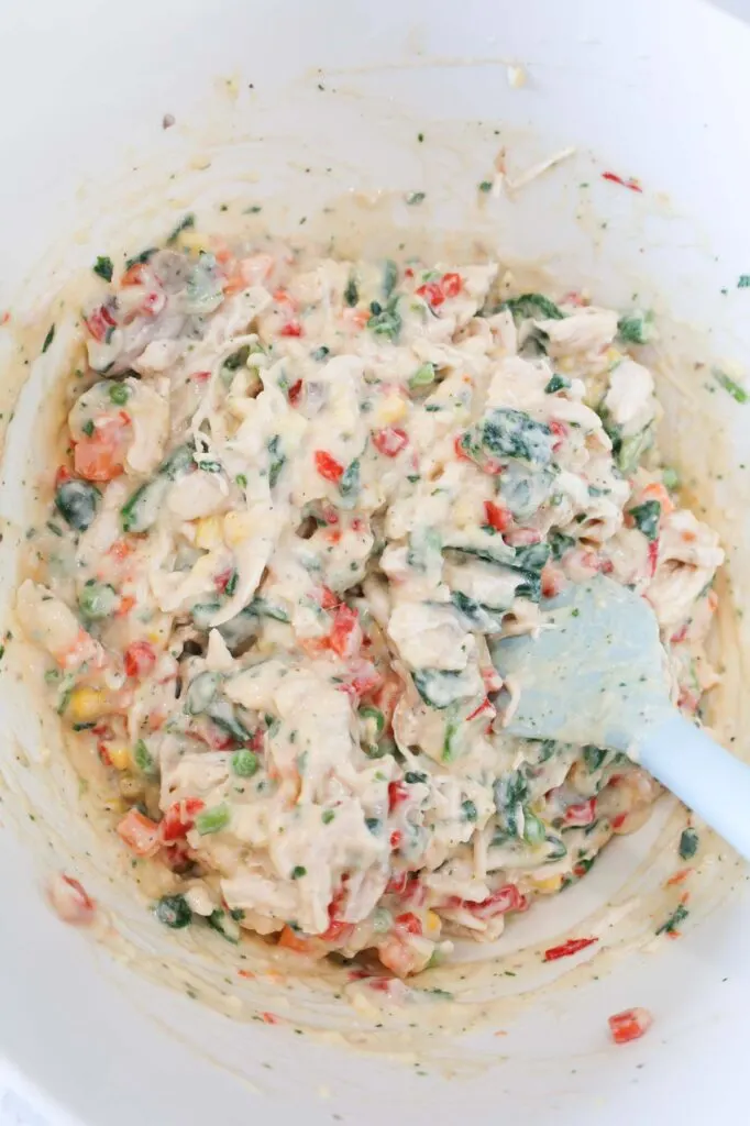 stirring creamy chicken and vegetable mixture in a mixing bowl