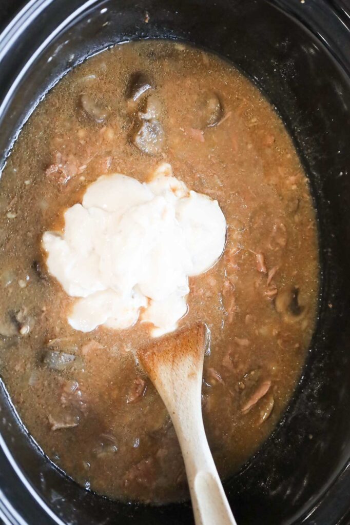 condensed cream of mushroom soup added to slow cooker with beef stroganoff mixture