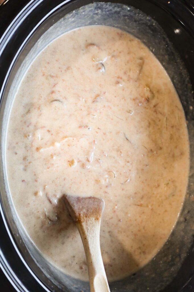 stirring sour cream into beef stroganoff mixture in a Crock Pot