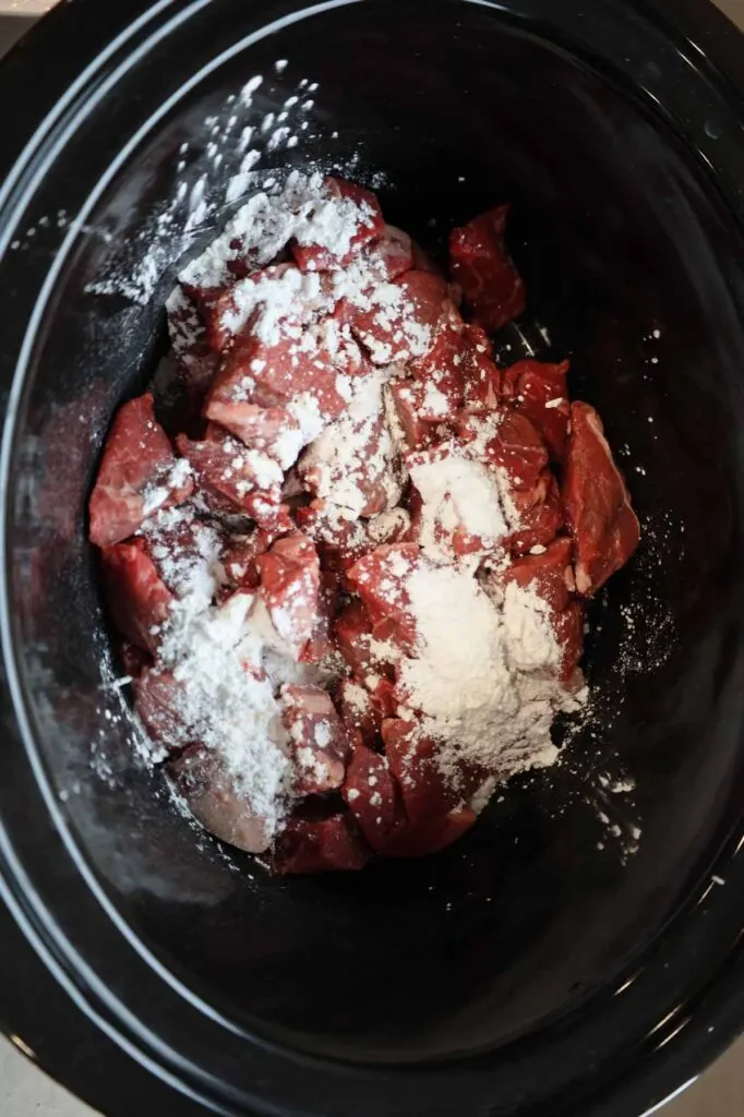 corn starch on top of stewing beef chunks in a slow cooker