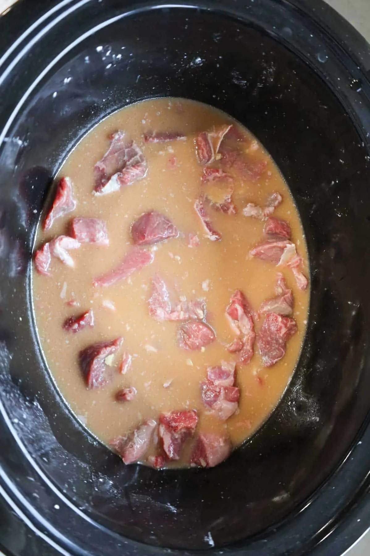 stewing beef chunks in a beef broth and cornstarch mixture in a slow cooker
