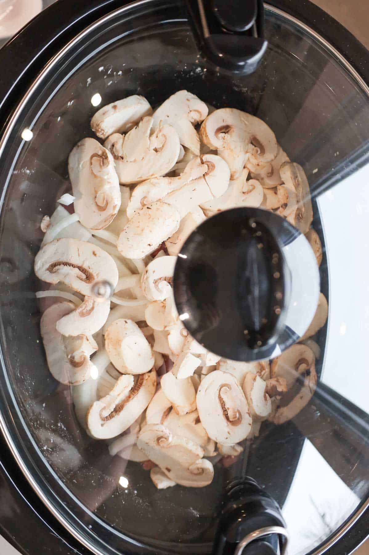 lid on Crock Pot containing beef stroganoff ingredients