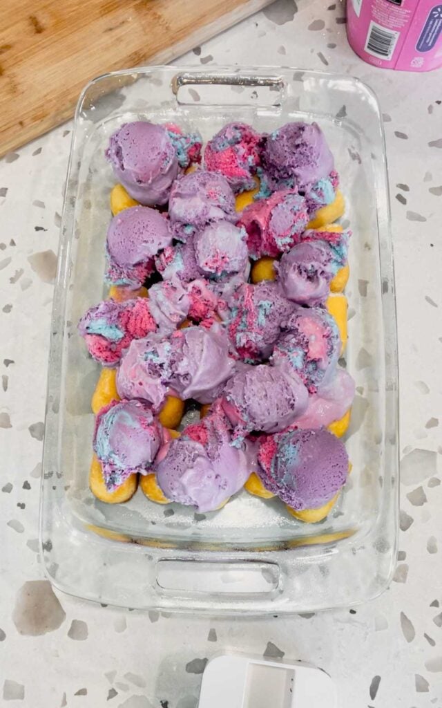 scoops of cotton candy ice cream on top of twinkies in a baking dish