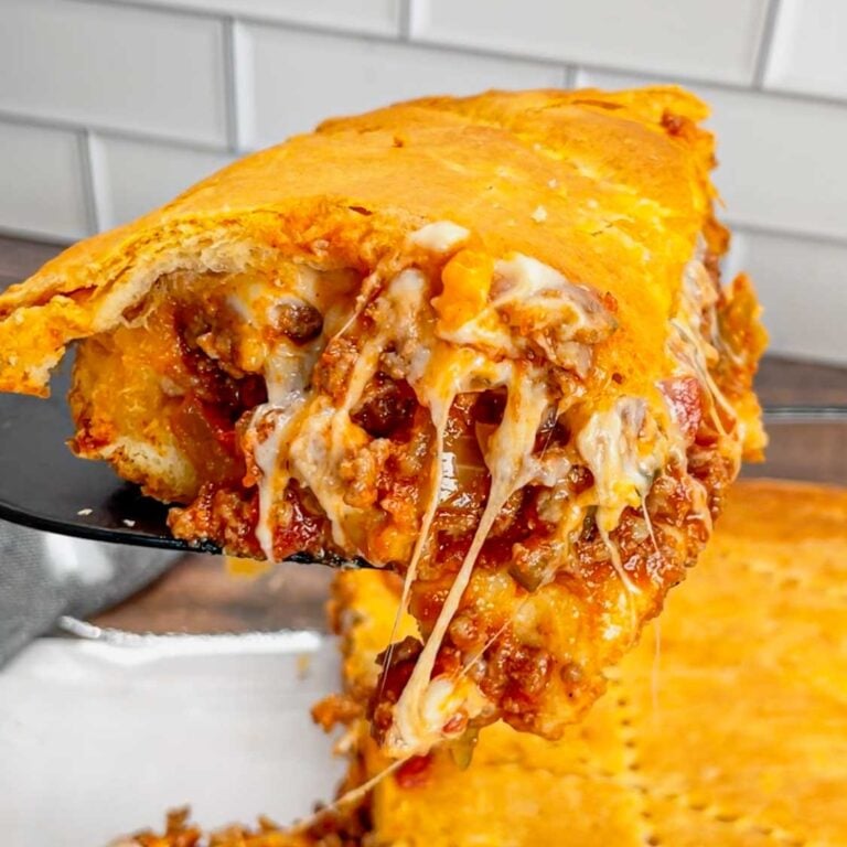 Crescent Roll Cheeseburger Casserole is a hearty ground beef dinner recipe made with layers of Pillsbury crescent roll dough and a ground beef filling loaded with onions, pickles, tomatoes, ketchup, mustard and shredded cheese.