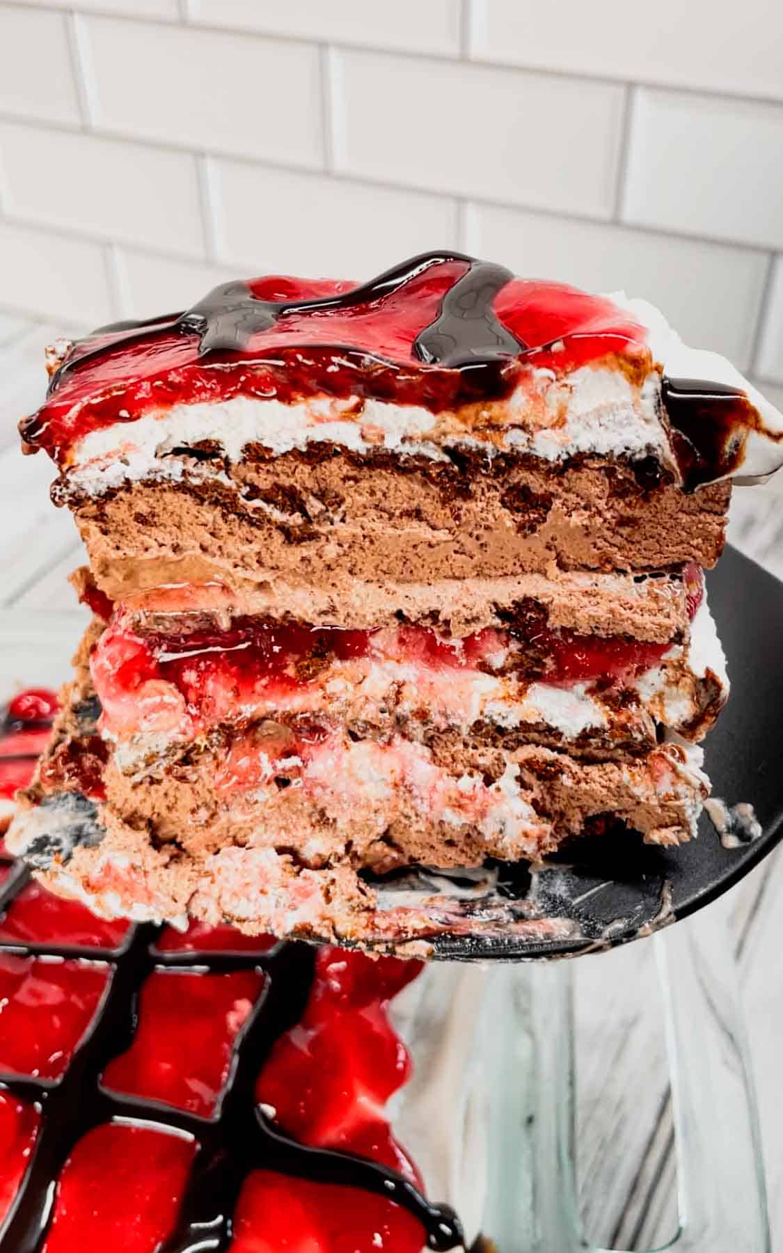 Black Forest Ice Cream Sandwich Cake is an easy 4 ingredient no bake dessert recipe made with chocolate ice cream sandwiches, whipped topping, cherry pie filling and chocolate sauce.