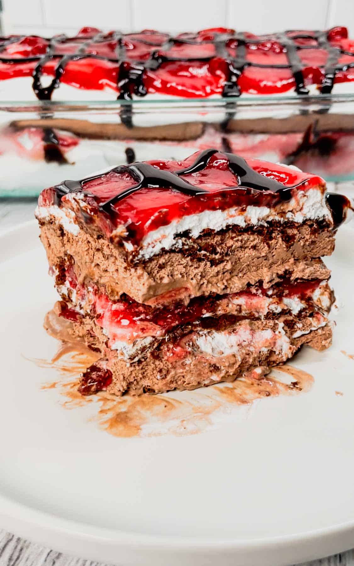 Black Forest Ice Cream Sandwich Cake is an easy 4 ingredient no bake dessert recipe made with chocolate ice cream sandwiches, whipped topping, cherry pie filling and chocolate sauce.