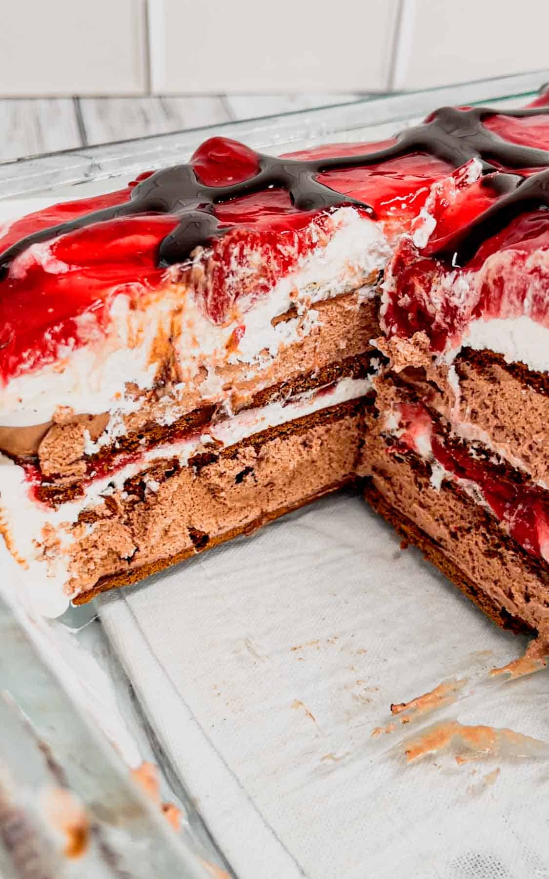 Black Forest Ice Cream Sandwich Cake is an easy 4 ingredient no bake dessert recipe made with chocolate ice cream sandwiches, whipped topping, cherry pie filling and chocolate sauce.