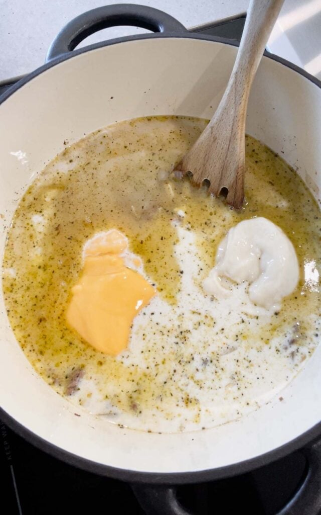 half and half cream, chicken broth, cheddar soup and cream of bacon soup added to Dutch oven with cooked ground beef
