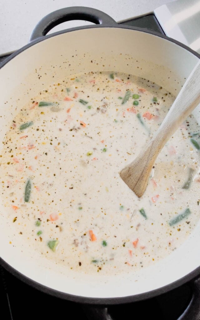 stirring frozen mixed veggies into creamy soup mixture