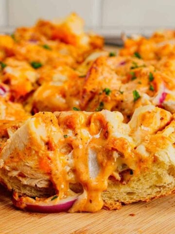 Cajun Chicken Alfredo Garlic Bread is an easy dinner recipe loaded with chunks of rotisserie chicken, Cajun seasoning, creamy alfredo sauce, mozzarella and cheddar cheese all baked on top of a loaf of Italian bread spread with garlic butter.