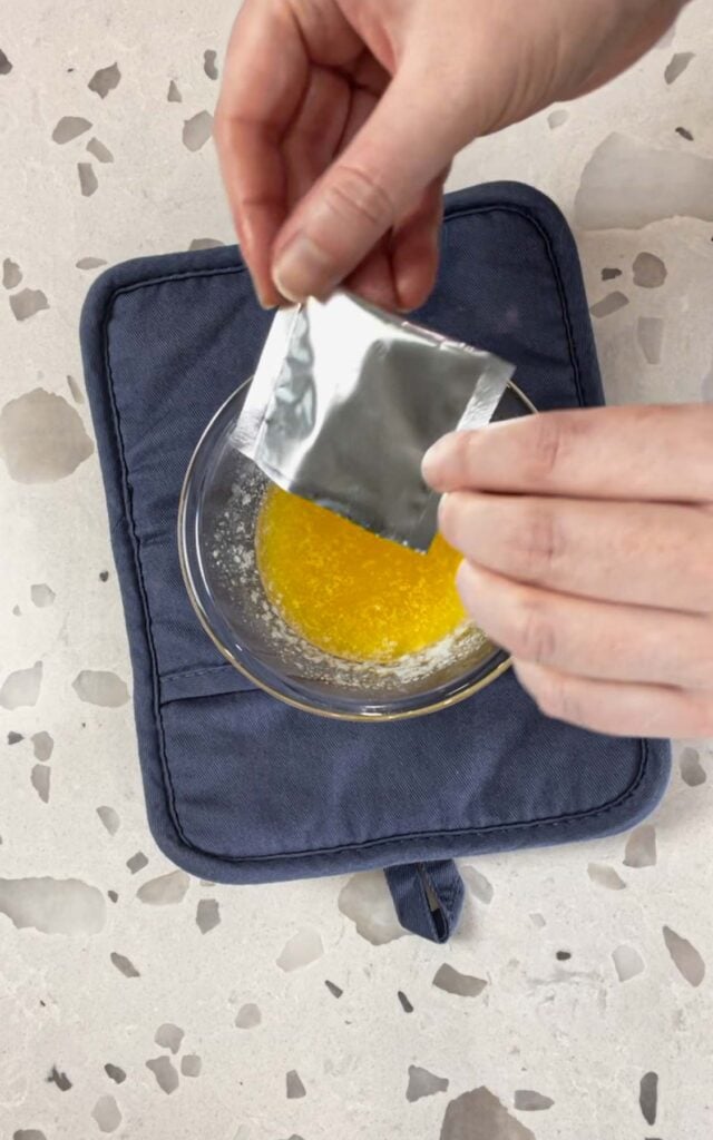 adding cheddar bay biscuit seasoning to a bowl with melted butter