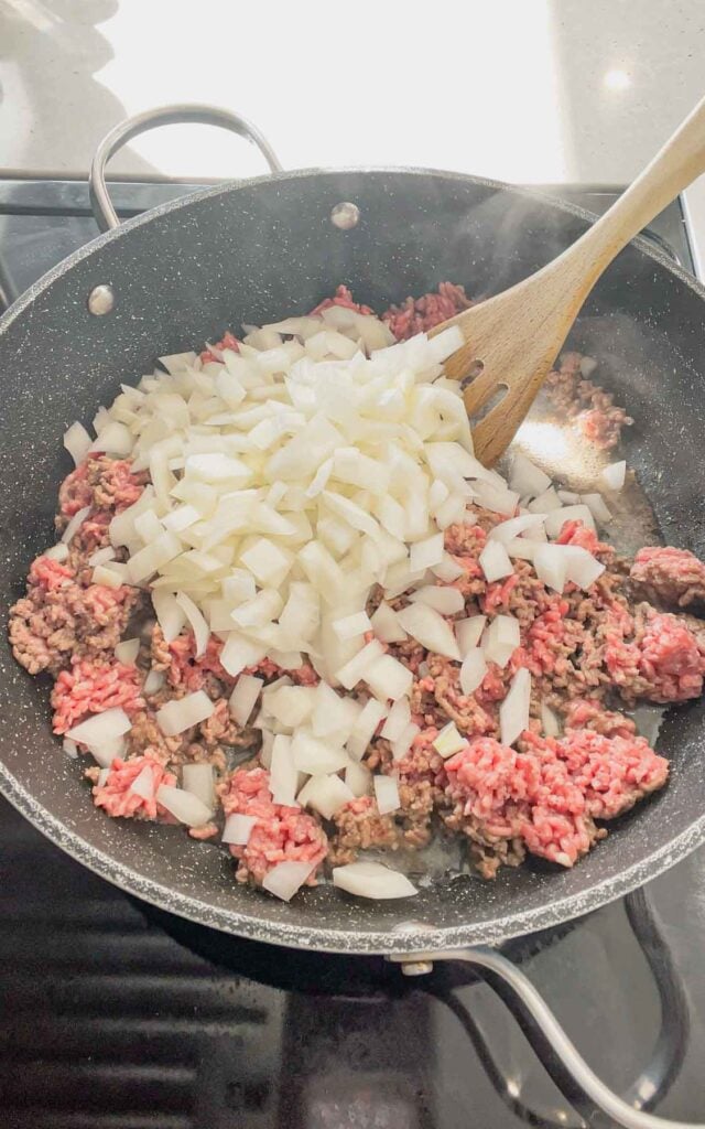 diced onions added to skillet with raw ground beef
