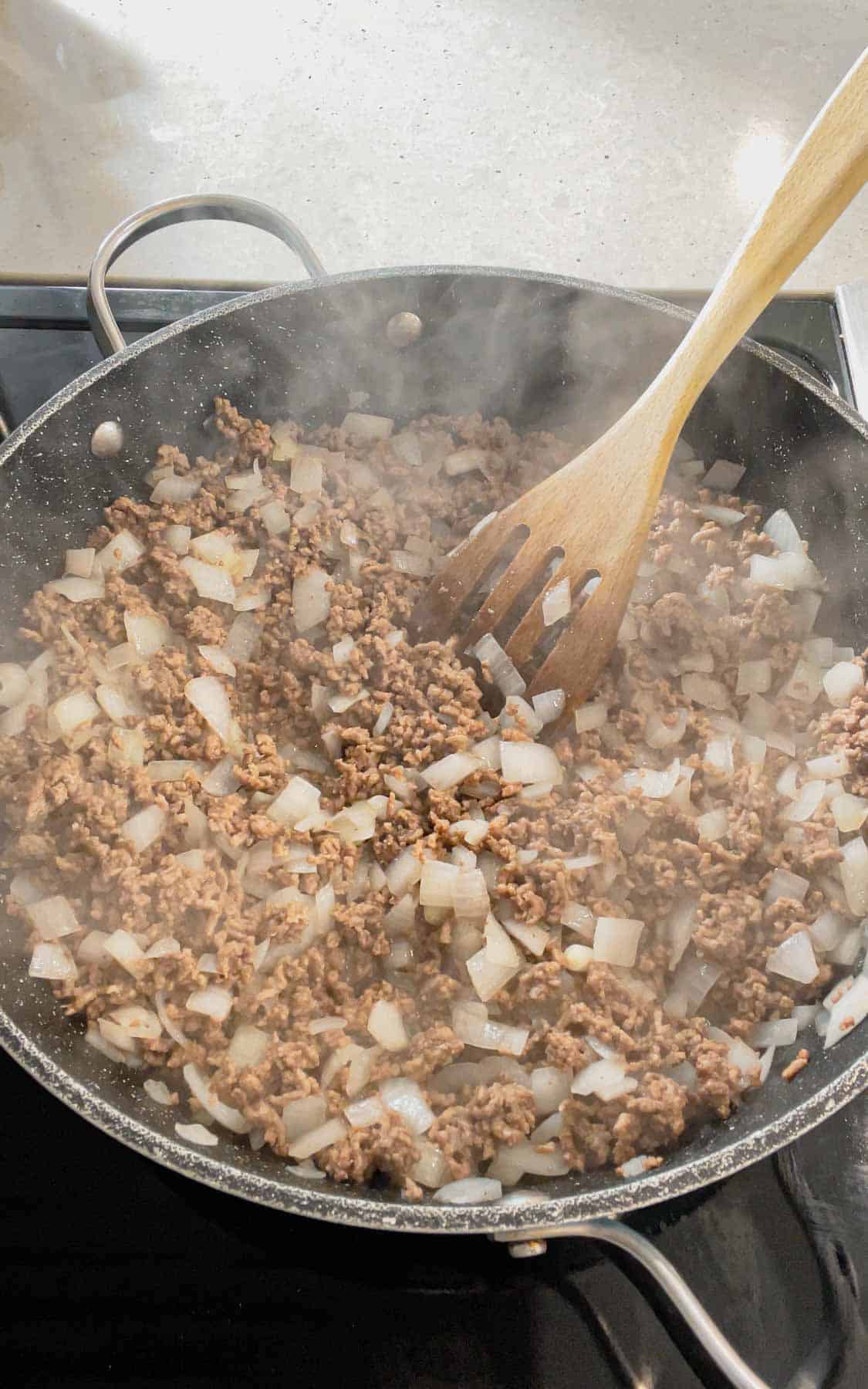 cooked ground beef and diced onions in a skillet