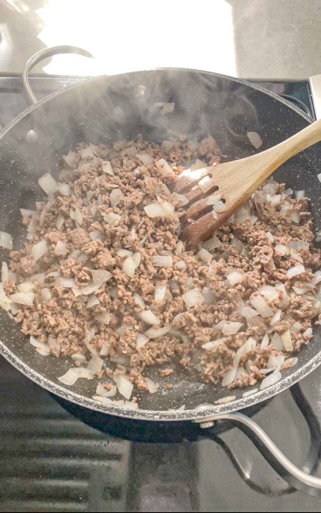 cooked ground beef and onions in a skillet