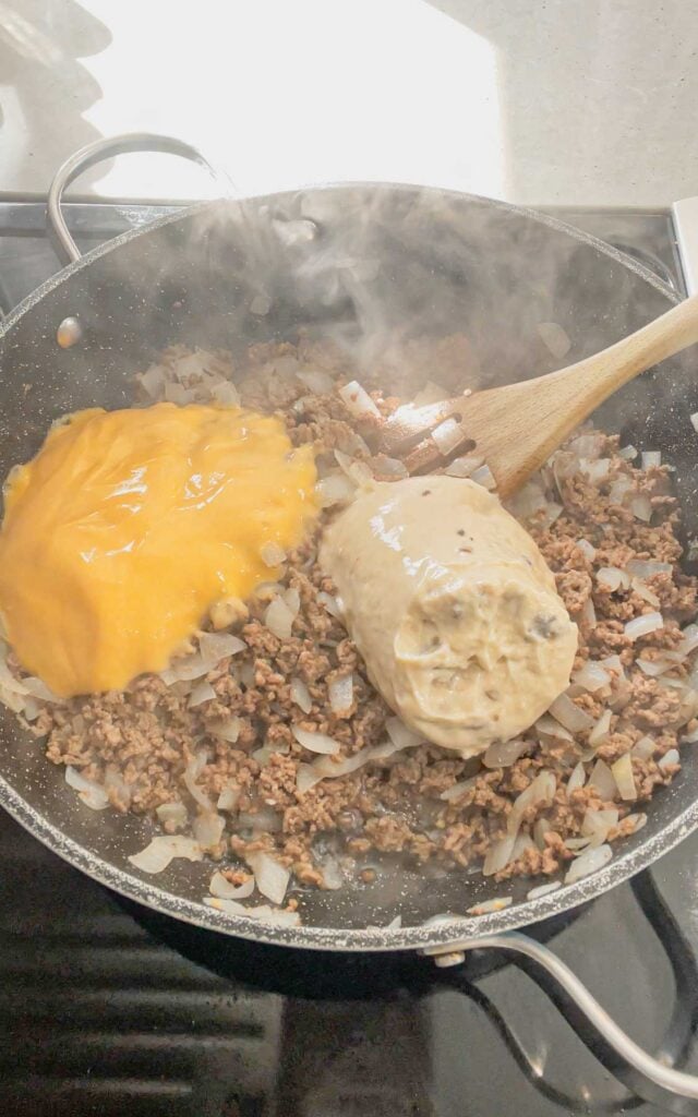 cheddar soup and cream of mushroom soup added to skillet with cooked ground beef